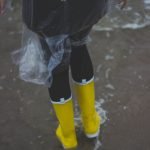 person wearing clear plastic raincoat and pair of yellow rainboots